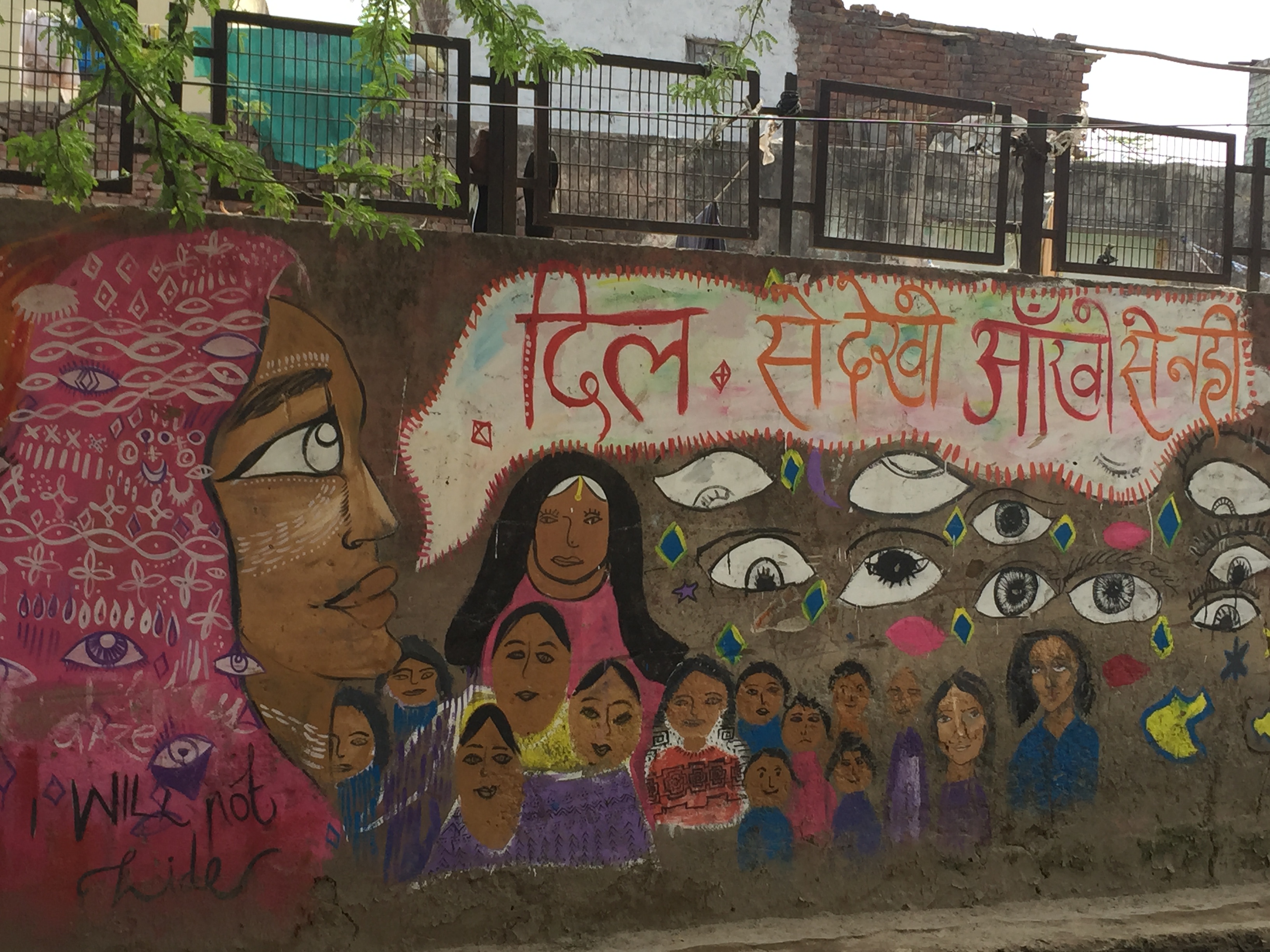 A Safecity mural, depicting images of women staring at the viewer. "I will not hide." is seen on the left.