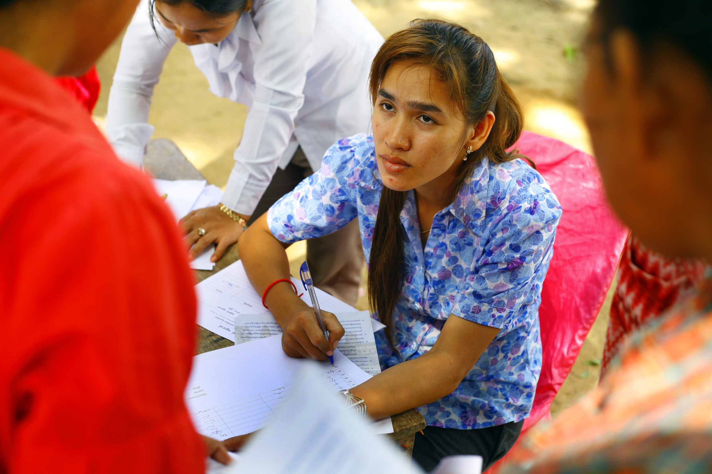 Cambodia Bridges to Justice employee fills out paperwork for a client