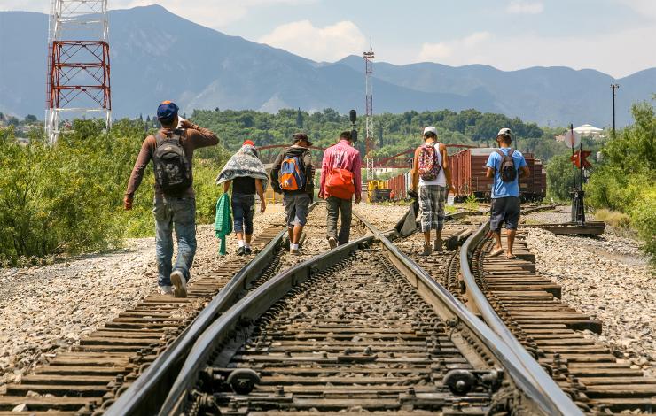 A group of Central American people walking along train tracks as they head north 