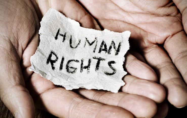 The word "Human Rights" on a piece of paper, being held in a person's hands